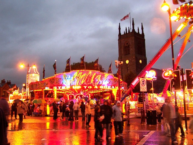 Market Place, Ilkeston, Derbyshire, seen from the southwest on a rainy Friday evening during the Charter Fair, with St Giles' parish church on the…